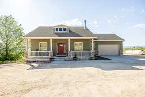 View of front of property with concrete driveway, a garage, covered porch, and roof with shingles