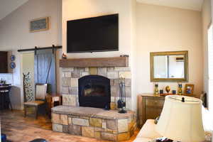 Living area featuring a barn door, wood finished floors, and high vaulted ceiling