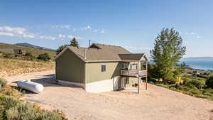 Back of property featuring a deck with mountain view, roof with shingles, and a patio area