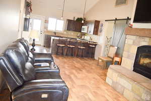 Living room featuring a barn door, light wood-style flooring, and high vaulted ceiling