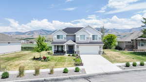 View of front facade featuring concrete driveway, a garage, covered porch, a mountain view, and a front yard