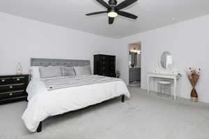 Bedroom with carpet floors, ensuite bath, and a ceiling fan