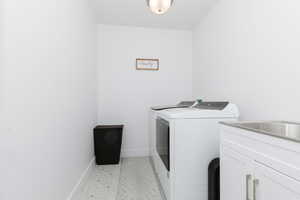 Washroom featuring separate washer and dryer and cabinet space