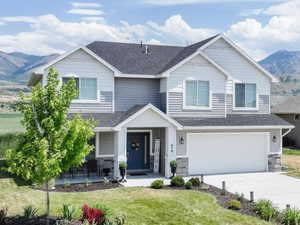 View of front of house with a mountain view, driveway, an attached garage, a front lawn, and covered porch
