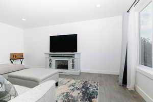 Living room with wood finished floors, recessed lighting, and a fireplace