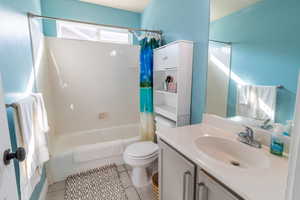 Bathroom featuring shower / bath combination with curtain, vanity, and tile patterned flooring