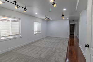 Spare room with track lighting, recessed lighting, and dark wood finished floors