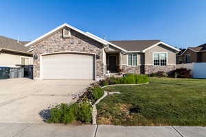 Single story home with stone siding, concrete driveway, a garage, and stucco siding