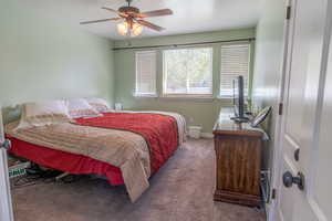 Carpeted bedroom featuring a ceiling fan and baseboards