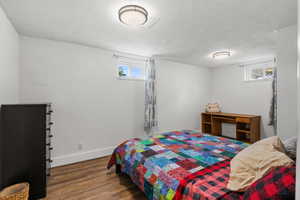 Bedroom with wood finished floors, multiple windows, and a textured ceiling