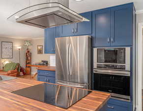 Kitchen featuring wood counters, black appliances, island range hood, blue cabinets, and ornamental molding