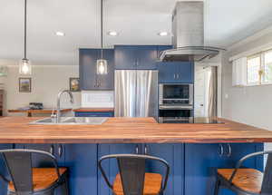 Kitchen with butcher block countertops, island range hood, black appliances, crown molding, and blue cabinets