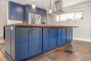 Kitchen with freestanding refrigerator, wood counters, island exhaust hood, blue cabinets, and ornamental molding