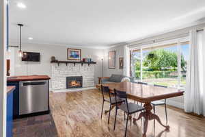 Dining space with ornamental molding, a stone fireplace, recessed lighting, and dark wood finished floors