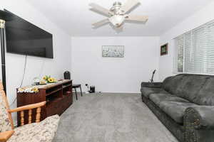 Living room featuring carpet flooring and a ceiling fan