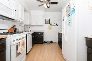 Kitchen featuring white appliances, light wood finished floors, a ceiling fan, white cabinets, and light countertops