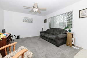 Carpeted living room featuring ceiling fan