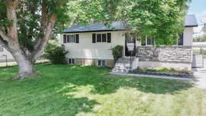View of front of property with a front yard, a metal roof, and stone siding