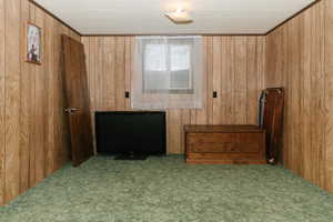 Carpeted bedroom featuring wooden walls