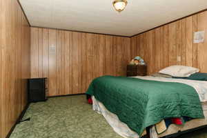 Bedroom with wood walls and carpet