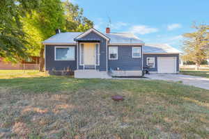 View of front of house with a chimney, an attached garage, a metal roof, and concrete driveway