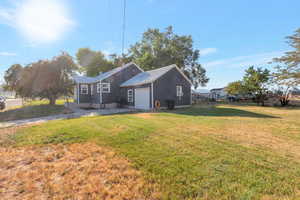 Rear view of property featuring a lawn, a garage, and a metal roof