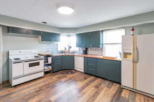 Kitchen with white appliances, backsplash, and dark wood-style flooring