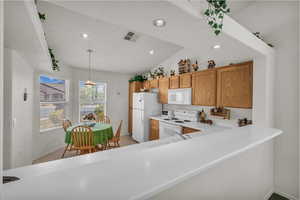 Kitchen featuring white appliances, light countertops, decorative light fixtures, recessed lighting, and lofted ceiling
