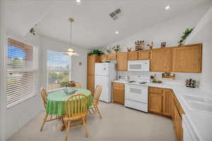 Kitchen with white appliances, vaulted ceiling, pendant lighting, light countertops, and recessed lighting