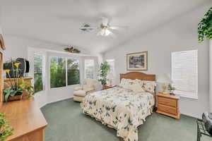 Carpeted bedroom featuring vaulted ceiling and ceiling fan