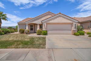 View of front of house with an attached garage, a tile roof, driveway, a front yard, and stucco siding