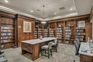 Carpeted home office featuring wall of books, built in features, a tray ceiling, recessed lighting, and wooden walls