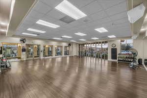 Gym with a paneled ceiling and wood finished floors
