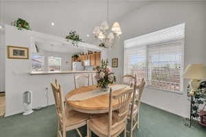 Carpeted dining space with a chandelier, recessed lighting, and vaulted ceiling