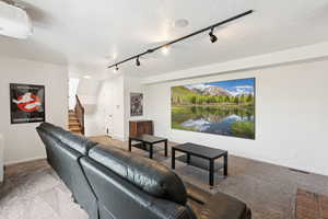 Carpeted living room featuring rail lighting and stairway