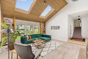 Living room has so much natural light with floor to ceiling windows & skylights