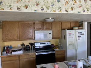 Kitchen with white appliances, light countertops, and brown cabinets