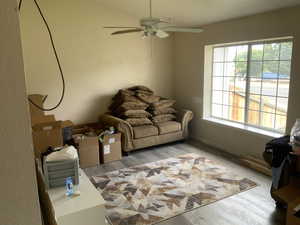 Living area with wood finished floors, healthy amount of natural light, and a ceiling fan