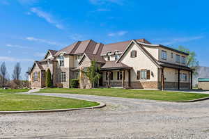 French country style house featuring stucco siding, curved driveway, stone siding, and a front yard
