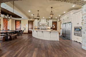 Kitchen featuring appliances with stainless steel finishes, premium range hood, a warming drawer, a chandelier, and dark wood finished floors