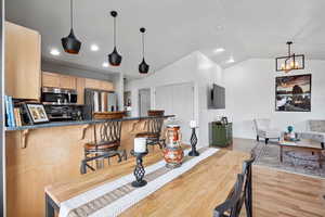 Dining area with lofted ceiling, light wood finished floors, recessed lighting, and a chandelier