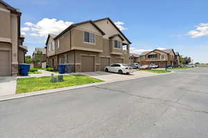 View of front of property with a residential view, stone siding, a garage, stucco siding, and driveway