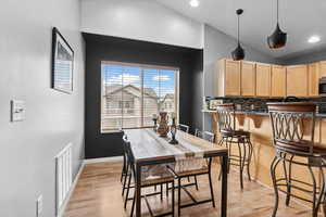 Dining room with light wood-style flooring, vaulted ceiling, and recessed lighting
