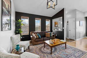 Living area with a chandelier, wood finished floors, and lofted ceiling