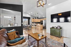 Living room featuring lofted ceiling, recessed lighting, light wood-style floors, and a chandelier