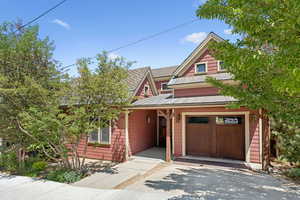 View of front of home with a standing seam roof, a metal roof, driveway, a garage, and a shingled roof