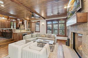 Living room with hardwood / wood-style flooring, wooden ceiling, wine cooler, a fireplace, and ceiling fan