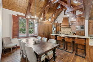 Dining area with a wooden ceiling with exposed beams, dark wood-type flooring, and high vaulted ceiling