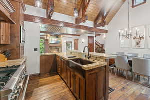 Kitchen featuring stainless steel appliances, wood ceiling, light wood-style flooring, open floor plan, and a warm lit fireplace