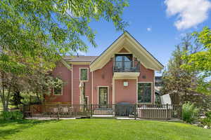 Back of house featuring a balcony, a yard, and a wooden deck